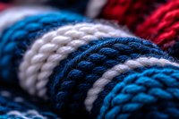 Macro close-up of knitted wool texture in blue, white and red colors showing detailed yarn pattern and weaving structure. Soft winter fabric background.