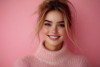 Young Caucasian woman with natural makeup and messy bun hairstyle wearing pink turtleneck sweater smiling against pink background. Positive genuine expression.