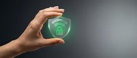Hand holding glowing green shield with lock and wifi symbol, representing secure wireless network protection and cybersecurity concept.