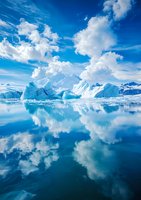 Majestic icebergs and snow-capped mountains reflected in calm arctic waters under dramatic white clouds and vibrant blue sky, creating mirror-like symmetry.
