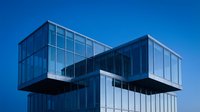 Modern cantilever office building with glass and steel construction against clear blue sky, suitable for corporate, architecture, and real estate marketing materials.