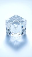 Crystal clear glass cube with geometric facets reflecting light on white background for luxury design and modern decor projects.