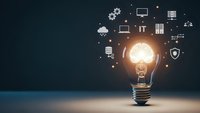 Glowing light bulb with technology icons floating around representing innovation, digital transformation and creative business solutions.