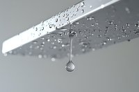 Water droplet falling from wet surface with splash and motion blur creating dynamic liquid photography for commercial use.