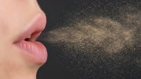 Woman exhaling breath with visible particles on dark background showing respiratory droplets and air transmission concept for health awareness.