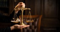 Golden scales of justice floating above open palm in dark courtroom setting with law books, symbolizing legal balance and judicial fairness concepts.