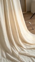 Elegant cream linen curtains flowing gracefully on wooden floor in modern minimalist interior with natural light and contemporary furniture.