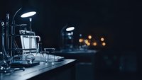 Professional laboratory equipment with glassware and microscope on research table in dark scientific workspace for medical analysis and experiments.