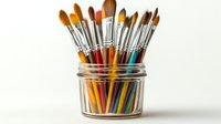 Collection of colorful art paintbrushes with wooden handles arranged in clear glass jar against white background, professional art supplies for painting and creative work.