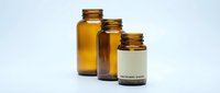 Three amber glass pharmaceutical bottles with screw caps arranged in descending size order on white background for medical packaging design.