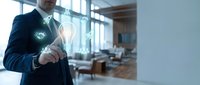 Senior businessman touching glowing lightbulb icon in modern office representing innovation and creative business solutions for corporate strategy.