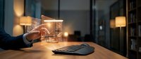 Man's hand touching glowing digital cube interface on wooden desk with keyboard and warm office lighting in background for technology and innovation concepts.
