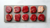 Assorted raw beef steaks arranged on a stone board, showcasing marbling and fresh cuts for culinary, restaurant menu, and food blog use.