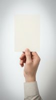 Hand holding blank cream paper card against neutral background for business presentation mockup design templates.