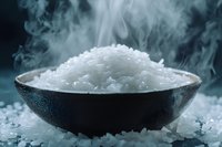 Steaming bowl of sea salt crystals on dark background with dramatic smoke effect and scattered salt grains, moody food photography styling.