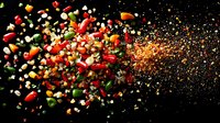Explosive mix of colorful spices, chili peppers, garlic and herbs scattered on black background with dynamic motion effect and golden spice powder burst.