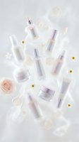 Luxury skincare and cosmetic bottles with lavender and white caps arranged on white background with fresh flowers and pearls for beauty product marketing.