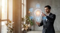 Young professional businessman in suit presenting innovative technology concepts with glowing lightbulb and digital icons in modern office environment.