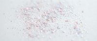 Scattered pink and silver glitter particles on white surface, suitable for cosmetics, beauty, celebration, and festive design projects.