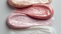 Shimmering cosmetic lip gloss swatches in metallic rose gold, pink, soft rose, and pearl white tones on white background for beauty product marketing.