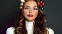 Young Asian woman with festive makeup, red lips, wearing white turtleneck sweater and Christmas ornament hair accessories against dark background. Holiday beauty portrait.