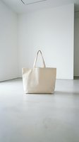 Blank cream canvas tote bag displayed in minimalist white gallery space, ready for branding, design mockups, and merchandise customization projects.