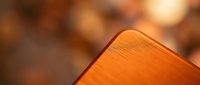 Close-up of warm orange wooden surface with natural grain texture and soft blurred background creating cozy atmospheric lighting for interior design projects.