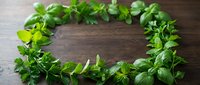 Fresh green basil leaves arranged in circular wreath shape on rustic wooden background for culinary herbs cooking ingredients natural organic food.