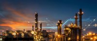 Industrial oil refinery complex at sunset with illuminated towers and processing units against dramatic orange and blue sky for energy sector presentations.