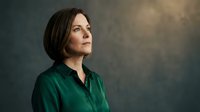 Professional middle-aged Caucasian businesswoman in green shirt looking upward with confident expression against textured background for corporate content.
