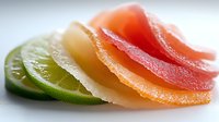 Sliced citrus fruits arranged in gradient from green lime to red grapefruit with sugar coating, suitable for food styling, culinary design, and beverage packaging.