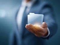 Businessman in suit holding glowing digital folder hologram in hand against blue background, representing data management and digital transformation.