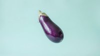 Fresh purple eggplant with stem on light blue background, suitable for food photography, culinary design, recipe blogs, restaurant menus, and healthy eating content.