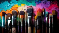 Paint brushes arranged in row against colorful oil paint palette background showing vibrant mixed colors and artistic texture. For art studio, creativity concepts.