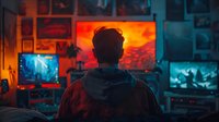 Young male gamer silhouette in hoodie sitting at gaming setup with multiple monitors displaying dramatic scenes, illuminated by vibrant orange and blue ambient lighting.
