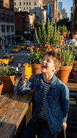 Happy young boy drinking orange juice on urban rooftop garden with potted plants and city street view. Child enjoying healthy beverage outdoors.