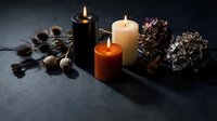 Autumn candles burning with pine cones, acorns and dried hydrangea flowers creating cozy seasonal atmosphere on dark surface for home decor.