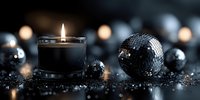 Elegant black candle with glowing flame beside decorative disco balls on dark glittery surface. Moody atmospheric lighting creates luxurious ambiance.