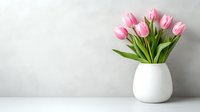Fresh pink tulips in modern white ceramic vase against light gray wall background, minimalist spring home decor arrangement with copy space for text.