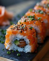 Fresh salmon sushi rolls topped with sesame seeds and green onions on black slate board, close up macro shot showing texture of rice and fish in Japanese cuisine.