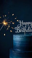 Dark blue layered birthday cake with glitter Happy Birthday topper and burning sparkler on dark background, festive celebration concept.