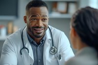 African American male doctor with stethoscope smiling warmly during patient consultation in medical office, showing professional care and attentive listening.