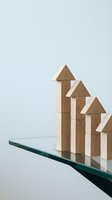 Wooden house blocks arranged in ascending row on glass surface representing growth, progress and real estate development concept for business presentations.