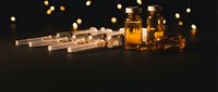 Medical syringes and amber glass vials on dark background with golden bokeh lights, pharmaceutical concept for healthcare and science.