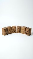 Wooden carved blocks displaying various human facial expressions from sad to happy isolated on white background for emotional concept designs.
