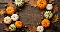 Autumn harvest frame with colorful pumpkins, maple leaves, acorns and pine cones arranged on rustic wooden background for seasonal decorating and thanksgiving.