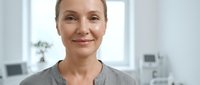 Middle-aged Caucasian woman healthcare professional smiling confidently in modern medical office environment for wellness and patient care concepts.