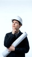 Caucasian male construction worker wearing white hard hat and dark work jacket, holding rolled blueprints while looking upward thoughtfully against white background for design projects.