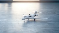Private white business jet model on reflective surface with dramatic lighting and shallow depth of field creating luxurious aviation atmosphere.