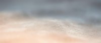 Soft sandy beach with gentle waves and foam washing ashore, suitable for travel, vacation, and coastal lifestyle marketing materials.